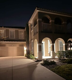 A residential building with a garage, arched entryways, and a balcony. - Luxury 6BR/6.5BA Solterra Villa / Private Pool, Theater & Minutes to Disney (Polk County)