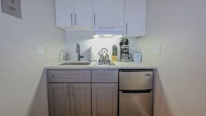 A compact kitchen with a sink, stove, and a small refrigerator. - Modern Simple Studio | South End (Boston)