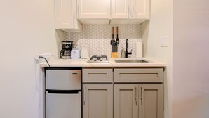 A compact kitchen with white cabinets, a built-in dishwasher, a coffee maker, and a toaster. - Peaceful South End Studio! (Boston)