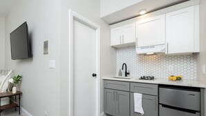Uma cozinha moderna com armários brancos, lava-louças de aço inoxidável e painel de azulejos.