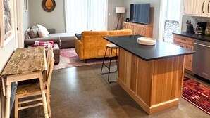 A cozy living room with a sofa, a small table, and a kitchen area with a counter and cabinets. - Cute 2-bedroom house in Jay, perfect for a relaxing getaway. (Jay)