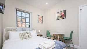 Un dormitorio con una cama, una mesa redonda, dos sillas y obras de arte en las paredes.