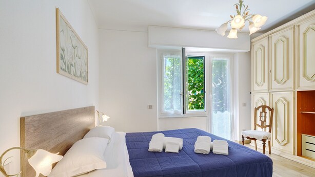Ein Schlafzimmer mit Bett, Fenster, Stuhl und Kleiderschrank.