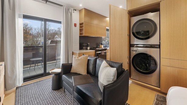 Un espacio habitable compacto con sofá, una mesa de centro, zona de comedor y lavadora y secadora integradas.