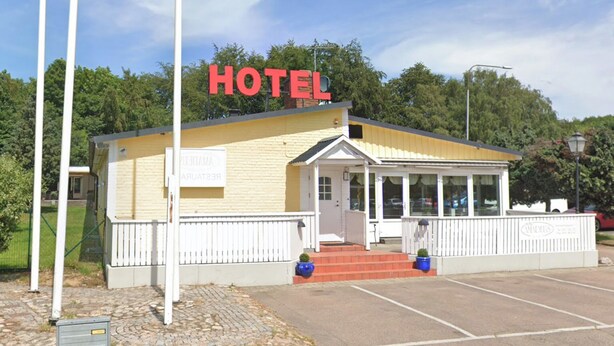 A small, single-story hotel with a yellow facade, a white entrance, and a sign that reads "HOTEL" in red letters. - Turtles Hotel (Angelholm)
