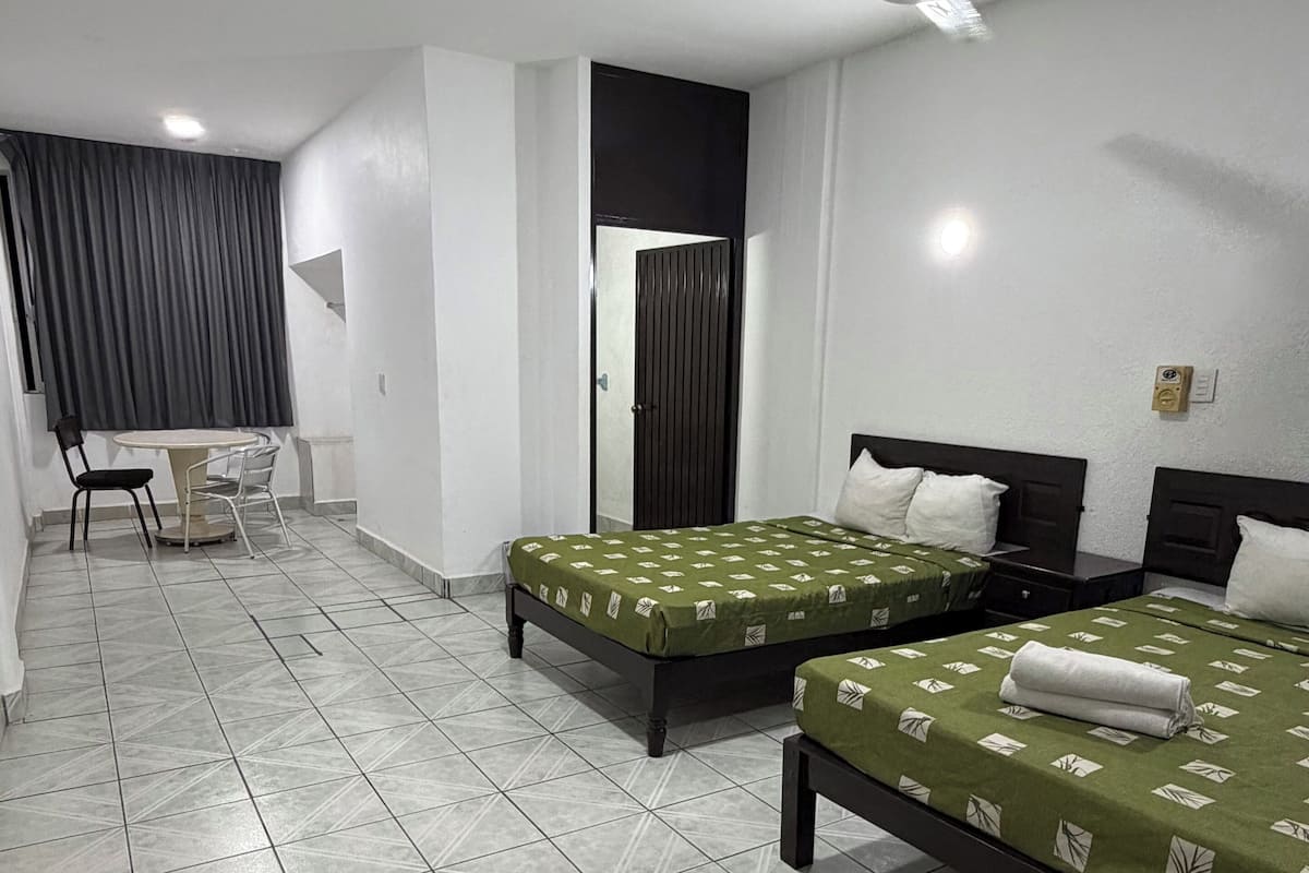 Une chambre d’hôtel avec deux lits, une petite table et une chaise.