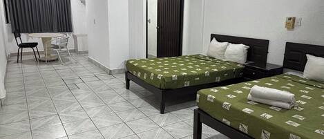 A hotel room with two beds, a small table, and a chair.