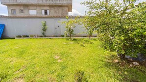 A grassy yard with a building in the background. - Casa Para 6 Pessoas com Churrasqueira em Peru be (Peruíbe)