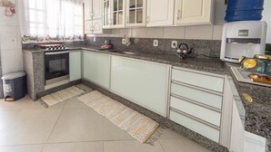 A kitchen with white cabinets, a granite countertop, a stove, and a sink. - Casa Para 6 Pessoas com Churrasqueira em Peru be (Peruíbe)