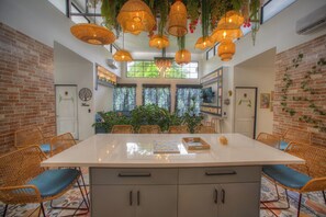 A spacious dining area with a large island, wicker chairs, and hanging wicker lamps. - La Fortuna Garden Luxury Smart House private swimming pool. (La Fortuna)
