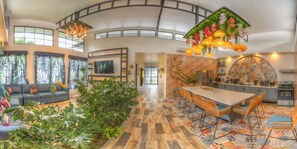 A spacious living area with a sofa, TV, and plants. There's a kitchen with a tiled backsplash and a dining area with chairs. - La Fortuna Garden Luxury Smart House private swimming pool. (La Fortuna)