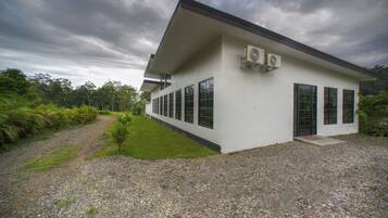 En modern byggnad med en vit fasad, stora fönster och luftkonditioneringsanläggningar.