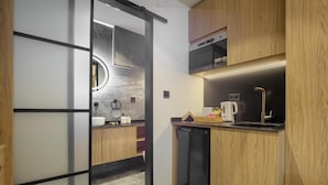 Una cucina compatta con mobili in legno, una lavastoviglie nera e un forno a microonde.