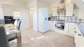 Een moderne keuken met witte kastjes, een roestvrijstalen oven en een koelkast.