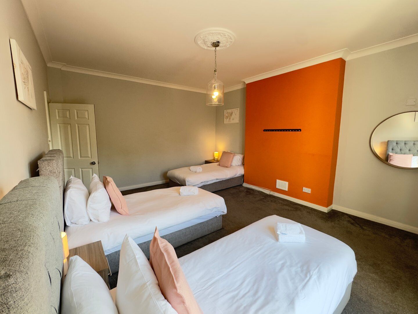 Une chambre d’hôtel avec deux lits simples, un canapé, un miroir et une porte.