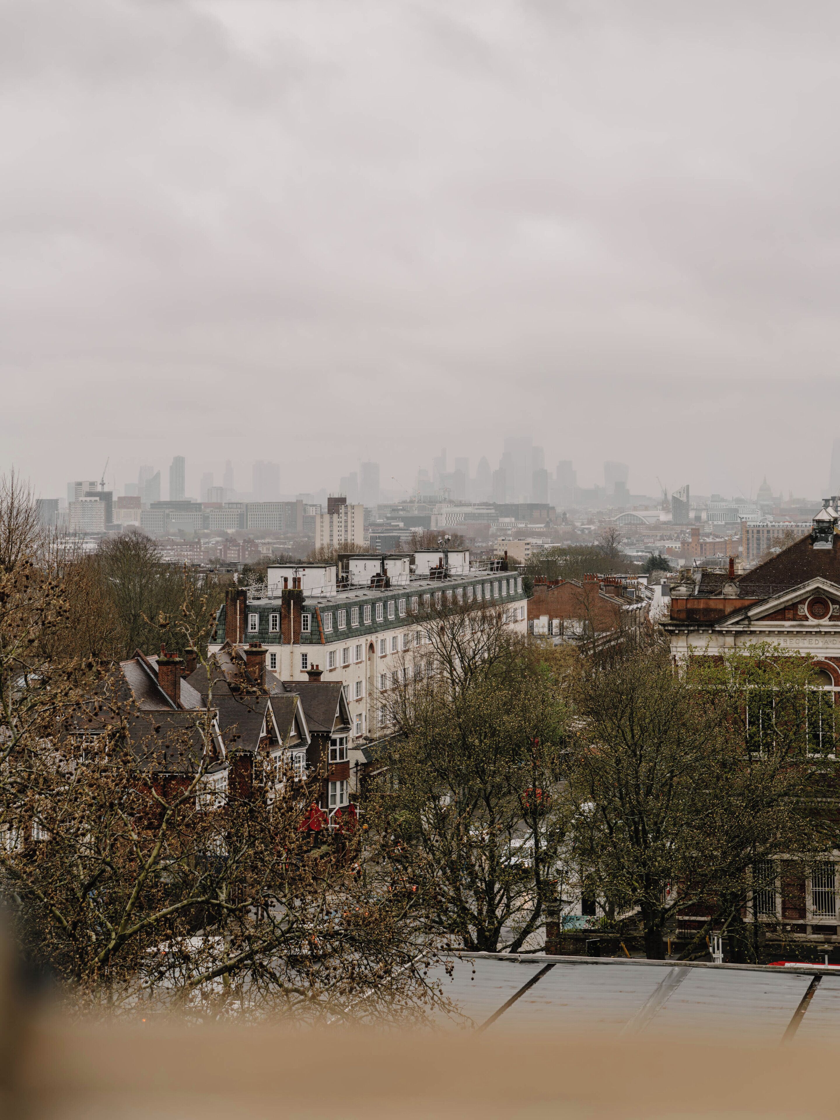 Une vue urbaine présentant divers bâtiments, dont un imposant bâtiment blanc surmonté d’un toit végétalisé et un bâtiment en briques rouges doté d’une façade blanche.