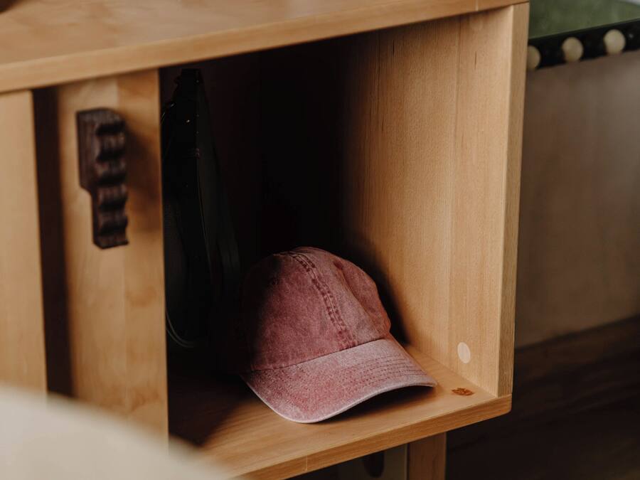 A wooden shoe rack with a pair of shoes and a cap.