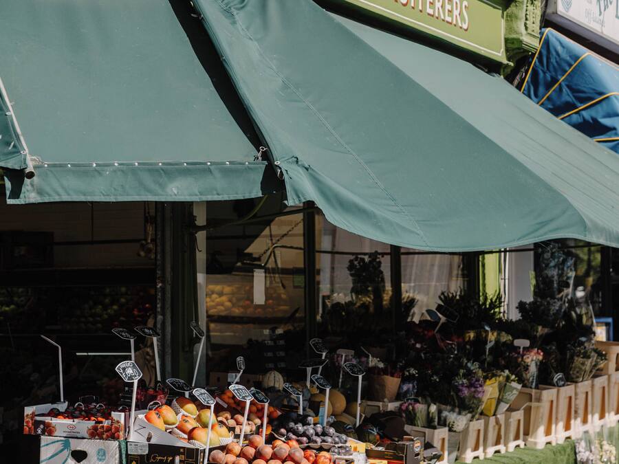 Een kraam met fruit, voorzien van een groen luifel waarop 'Crescent Fruiters' staat en het nummer '62'.