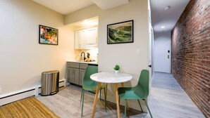 A compact living space with a kitchen, dining area, and a brick wall. - Studio Nestled in Back Bay! (Boston)
