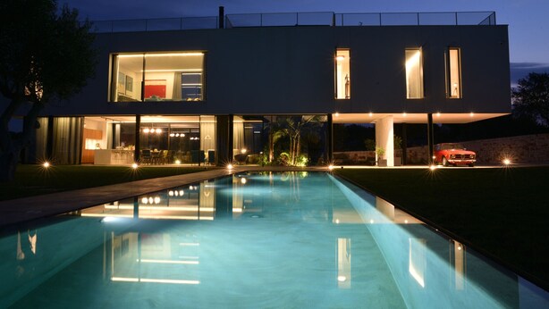 Een modern herenhuis met een zwembad op de voorgrond.