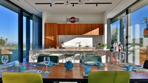 Een moderne keuken met houten kastjes, een Martini-bord en een eethoek met een tafel gedekt voor twee personen.