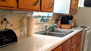 A kitchen with wooden cabinets, a stainless steel sink, and a countertop. - Peaceful 2-bedroom apartment with AC in charming Canaan (Canaan)