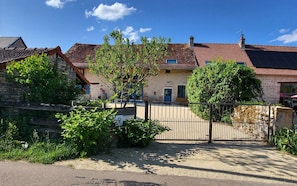 Ein Gebäude aus Stein mit Ziegeldach, einem verschlossenen Eingang und einem Baum davor.