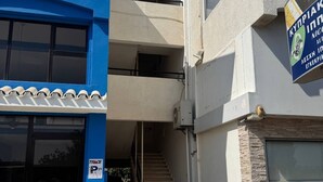 Een gebouw met een blauw-wit gevel, een zichtbare trap en een bord dat een bedrijf of dienst aangeeft.