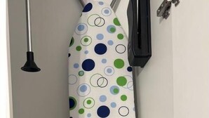 Een wit strijkplank met stippen, een strijkijzer en een klein strijkdoek.