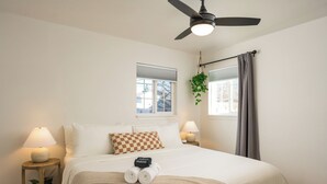 A neatly made bed with a checkered pillow, a bedside lamp, and a small potted plant on a wooden nightstand. - Spacious home w/HotTub, Game Room, Backyard Oasis - near Denver/Boulder+Pets OK! (Westminster)