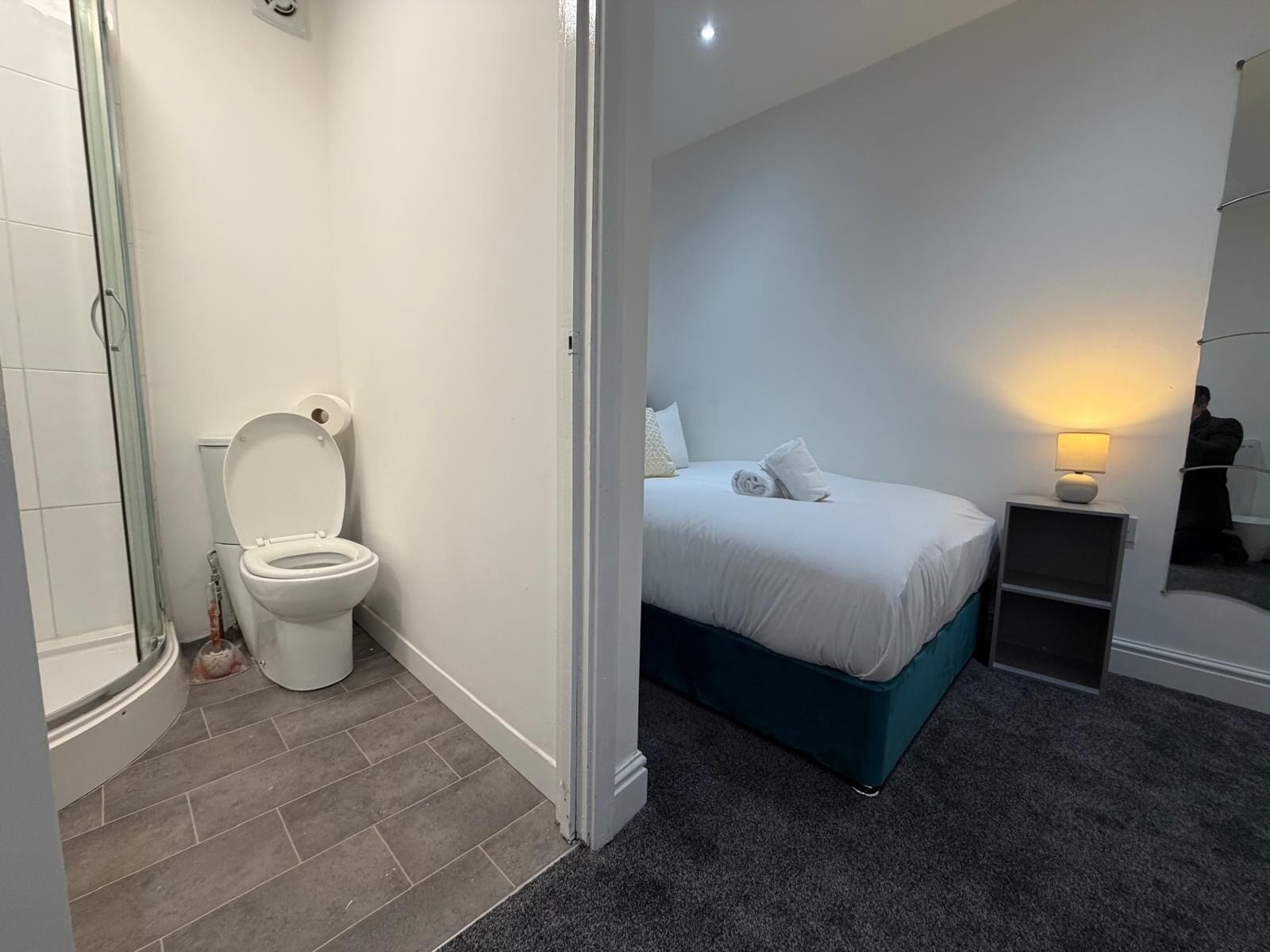 Une salle de bain moderne équipée de toilettes, d’une douche et d’un lit avec une tête de lit.