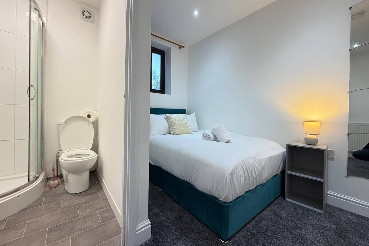 A modern bathroom with a glass shower enclosure, a white toilet, and a small window above the sink.