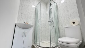 Un bagno moderno con cabina doccia in vetro, lavandino bianco e water.