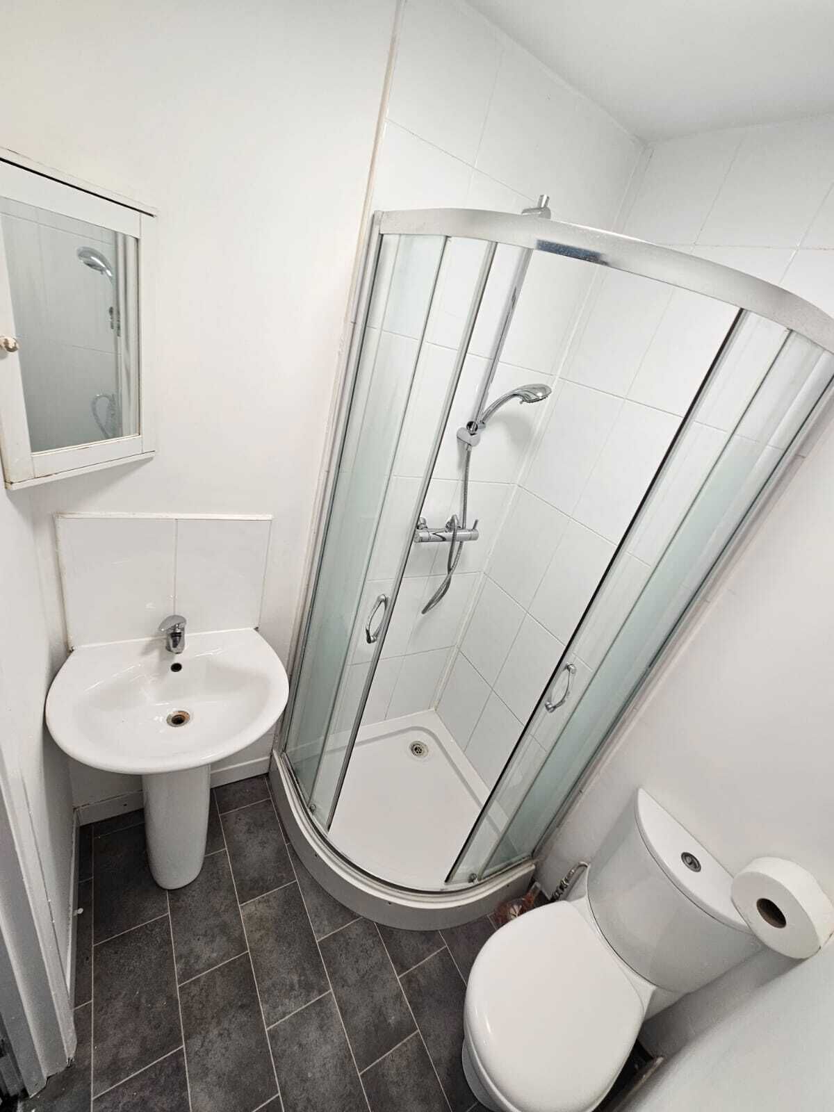 A bathroom with a glass-enclosed shower, a pedestal sink, and a toilet.