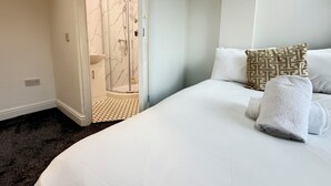 Una camera d'albergo con un letto, cabina doccia e bagno.