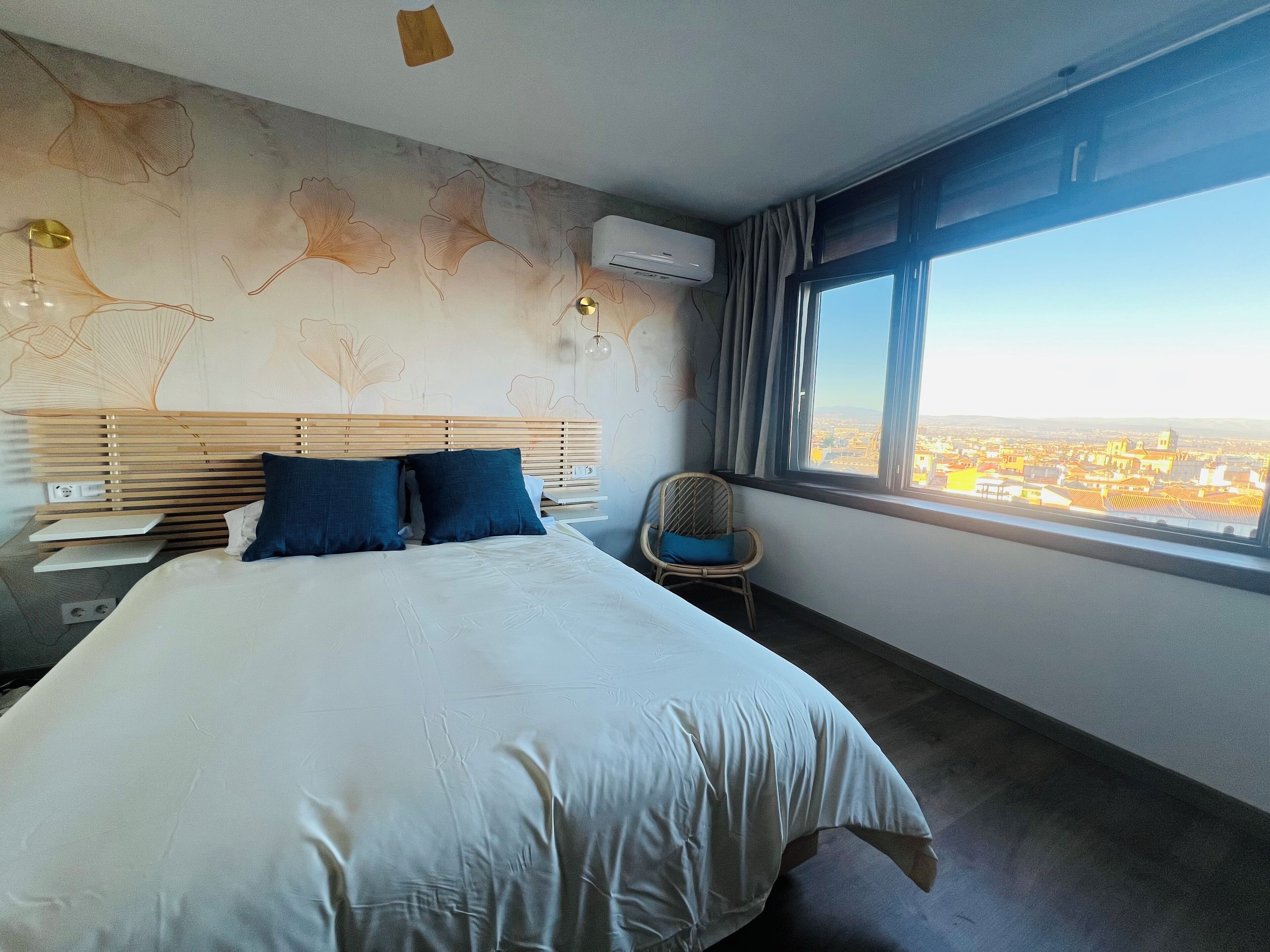 Een hotelkamer met een groot bed, een stoel, een bureau en een raam met uitzicht op de stad.