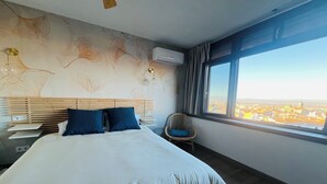 Een hotelkamer met een groot bed, een stoel, een bureau en een raam met uitzicht op de stad.
