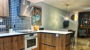 Een moderne keuken met een ingebouwde oven, een roestvrijstalen afzuigkap en een decoratieve spatwand.