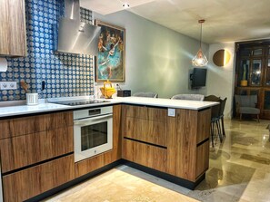A modern kitchen with a built-in oven, a stainless steel range hood, and a patterned backsplash. - Spectacular 3-Bedroom House Downtown with Unbeatable Views over Granada. (Granada)