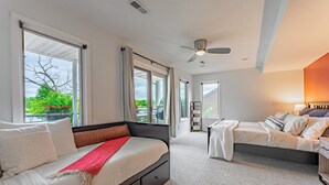 Une chambre moderne avec un grand lit, un petit canapé et un ventilateur de plafond.