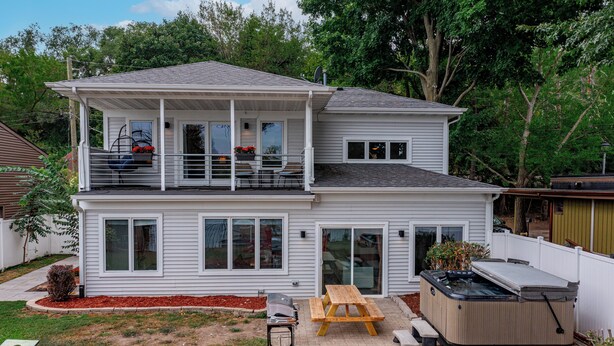 Une maison à deux étages dotée d’un patio, d’un jacuzzi et d’un barbecue.