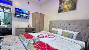 Ein modernes Schlafzimmer mit einem großen Bett, einem Fernseher und einem Bild an der Wand.