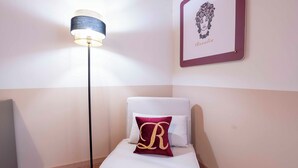 Una camera d'albergo con un letto, una lampada da terra e un quadro appeso al muro.