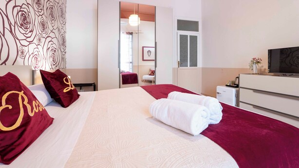 Una camera d'albergo con un letto grande, una TV, una scrivania e uno specchio.