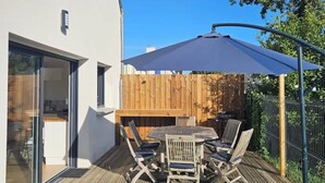 Een terras met een tafel en stoelen, een houten omheining en een helderblauwe lucht.