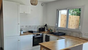 Een moderne keuken met witte kasten, een houten aanrechtblad en een groot raam dat natuurlijk licht binnenlaat.