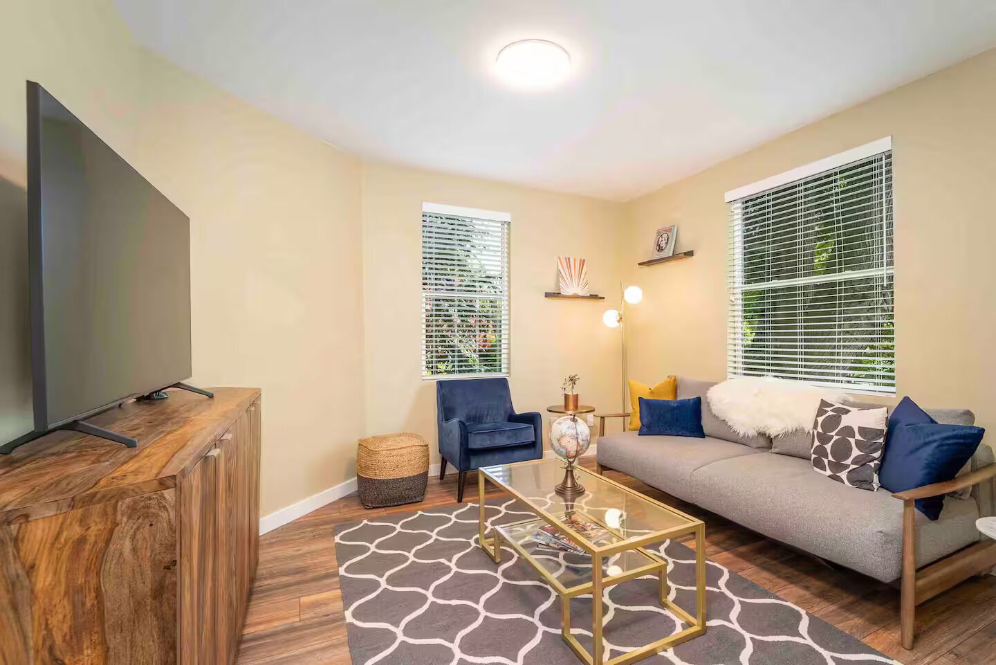 A living room with a flat-screen TV, two armchairs, a sofa, a coffee table, and a globe.