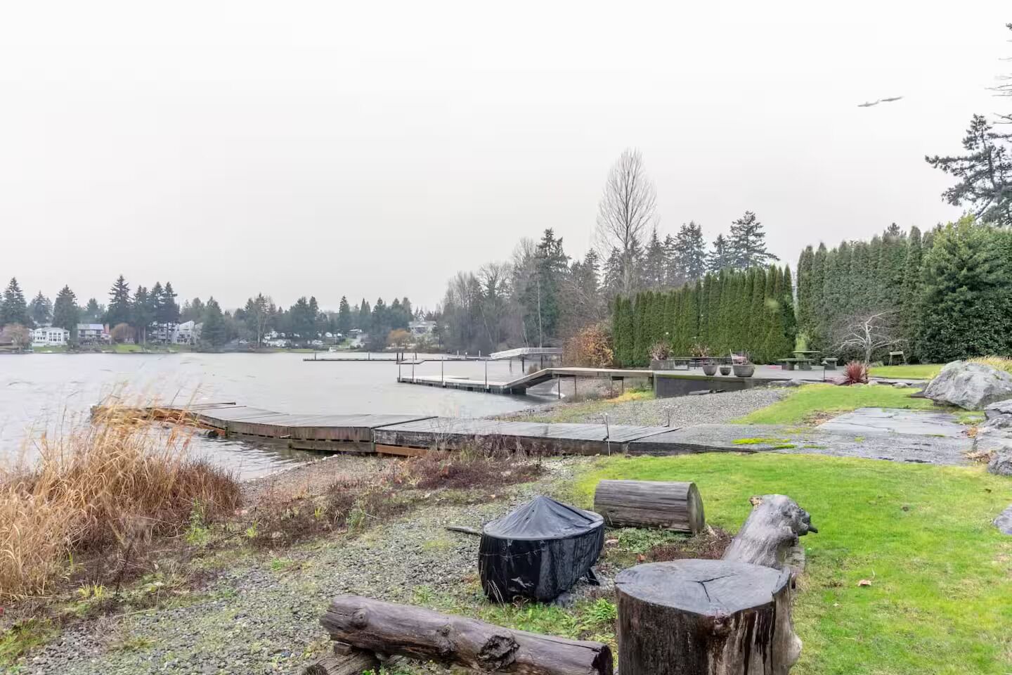 A lakeside park with wooden docks, a covered barbecue area, and a stone pathway.