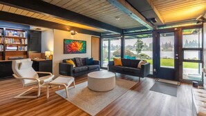 A modern living room with a fireplace, a coffee table, and a bookshelf. - Seattle Lake Front Oasis (SeaTac)