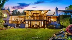 A modern two-story house with a glass facade, a covered patio, and a well-maintained lawn. - Seattle Lake Front Oasis (SeaTac)